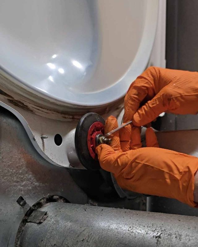 Gloved hands replacing a drum roller inside a dryer